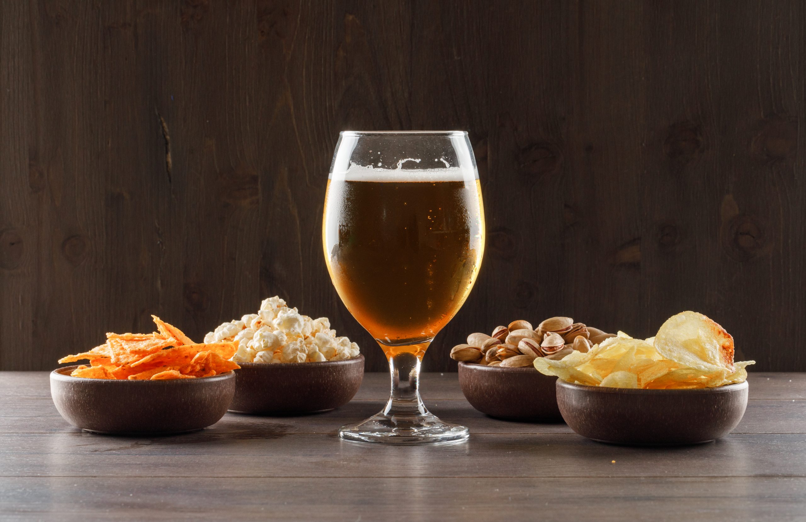 beer with junk food goblet glass wooden table side view scaled