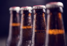 close up glass bottles of beer with ice on dark background