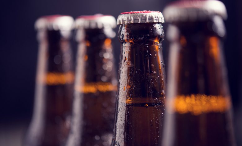 close up glass bottles of beer with ice on dark background